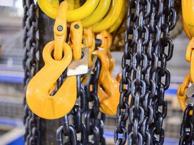 New chain cargo sling. Black steel chain and yellow cargo hooks. Abstract industrial background.